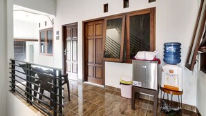 A hallway with a staircase, a water dispenser, and a trash bin.