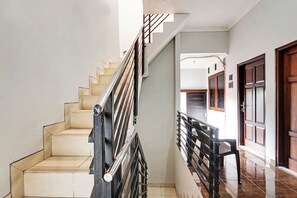 Una escalera con barandilla de metal, escalones color beige y una puerta de madera al final.