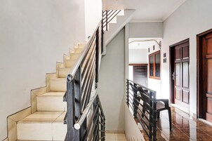 Una escalera con barandilla de metal y peldaños color beige que conduce a un piso superior.