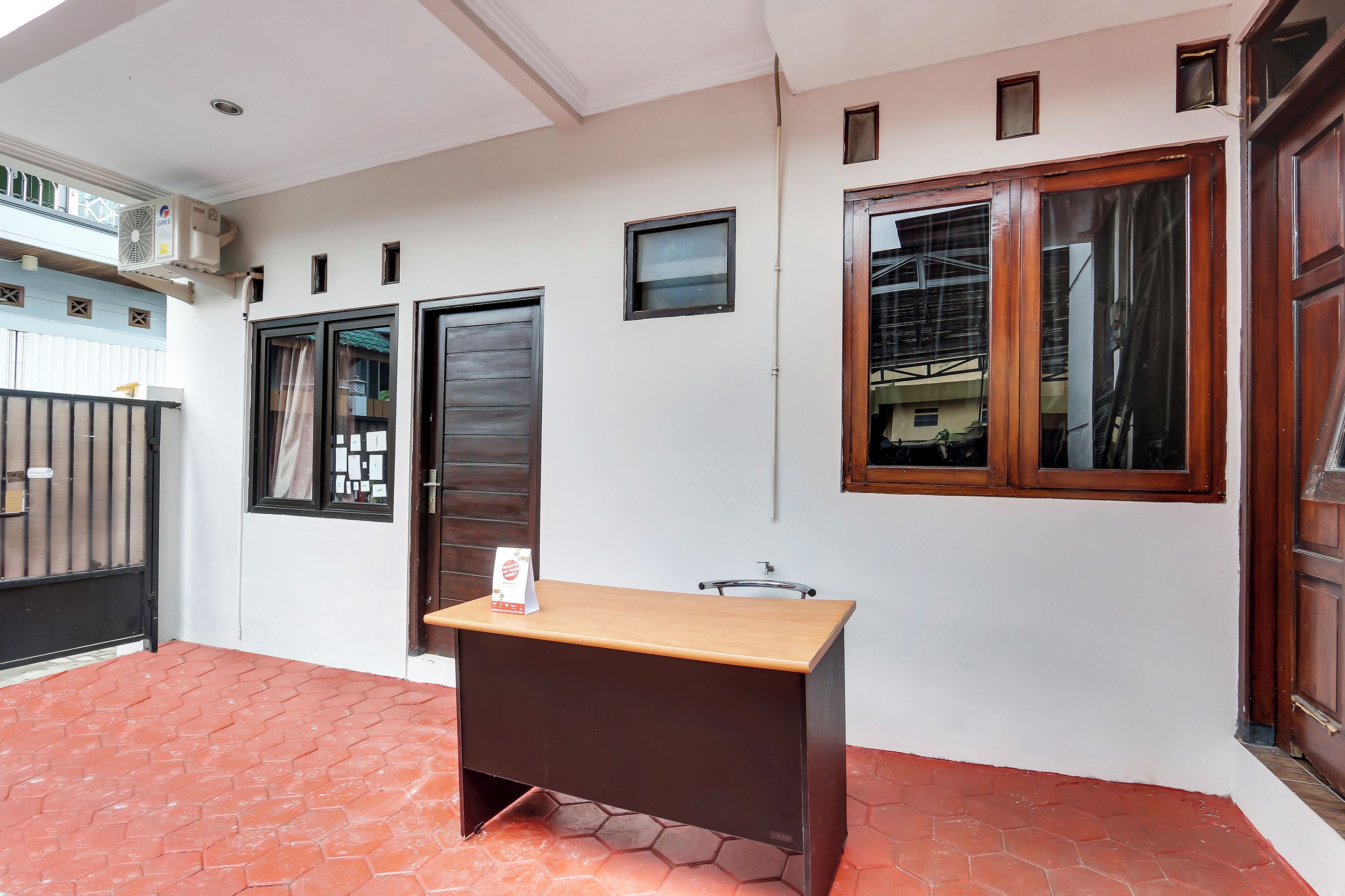 Una habitación con un escritorio, una ventana, una puerta y una pequeña mesa.