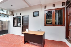 Une pièce avec un bureau, une fenêtre, une porte et une petite table.