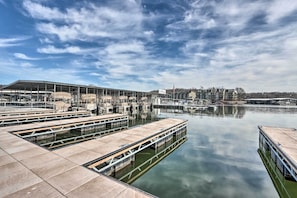 A marina with docked boats, a large building with a sign, and a calm water body. - Shootout Days Flow Into Swim-Up Bar Evenings (Osage Beach)