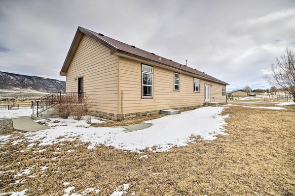 A single-story house with a sloped roof, a front porch, and a small front yard with snow patches.