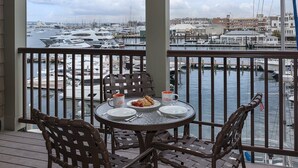 Ein Balkon mit Tisch für Zwei, mit Blick auf einen Yachthafen mit Booten und Gebäuden.