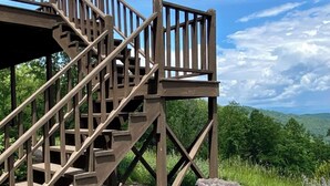 A wooden staircase leading to a deck with a stone bench and a birdbath. - Fall Colors | Prayer Mountain View Cabin | Fabulous Views from Fire Pit | Ping Pong (Moravian Falls)