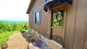 A house with a stone entryway, a welcome mat, and a view of the mountains. - Fall Colors | Prayer Mountain View Cabin | Fabulous Views from Fire Pit | Ping Pong (Moravian Falls)