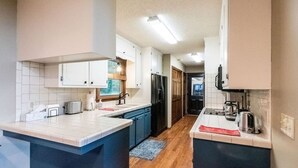 A modern kitchen with white and blue cabinetry, a central island, and a wooden floor.