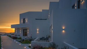 A modern building with a flat roof, a long pathway, and a garden with various plants and flowers. - El mar Naxos  (Naxos)