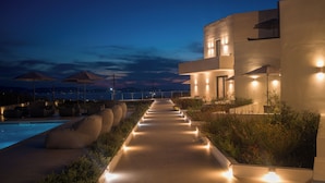 A modern resort with a pool, outdoor seating, and a view of the sea at dusk. - El mar Naxos  (Naxos)