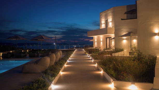 A modern resort with a pool, outdoor seating, and a view of the sea at dusk. - El mar Naxos  (Naxos)