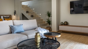 A modern living room with a sofa, a coffee table, a staircase, and a flat-screen TV. - El mar Naxos  (Naxos)