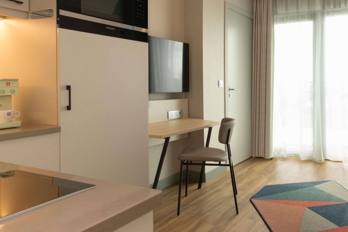 Een moderne keuken met een magnetron, een koffieapparaat en een eethoek met een tafel en stoelen.