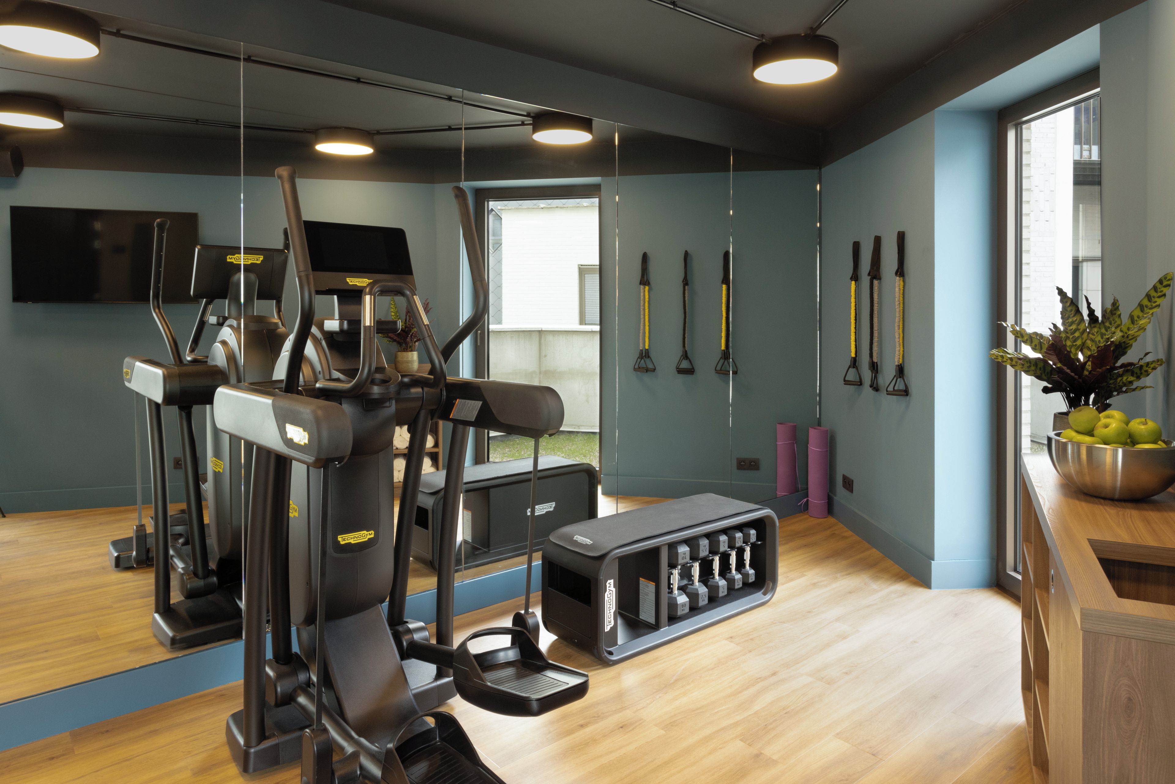 Une salle de sport équipée de matériel d’exercice, d’un miroir et d’une fenêtre.