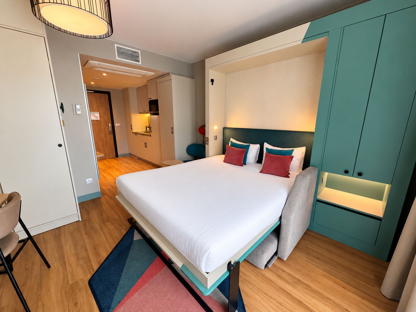 Una habitación de hotel moderna con una cama grande, un escritorio y un armario.