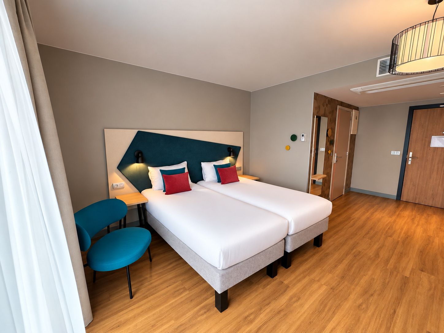 Een hotelkamer met een tweepersoonsbed, een bureau, een stoel en een kledingkast.