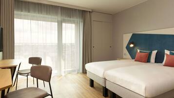 A hotel room with two beds, a desk, and a chair.