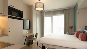 A modern hotel room with a bed, a desk, a chair, a TV, and a window with curtains. - Adagio Antwerp City Center (Antwerp)