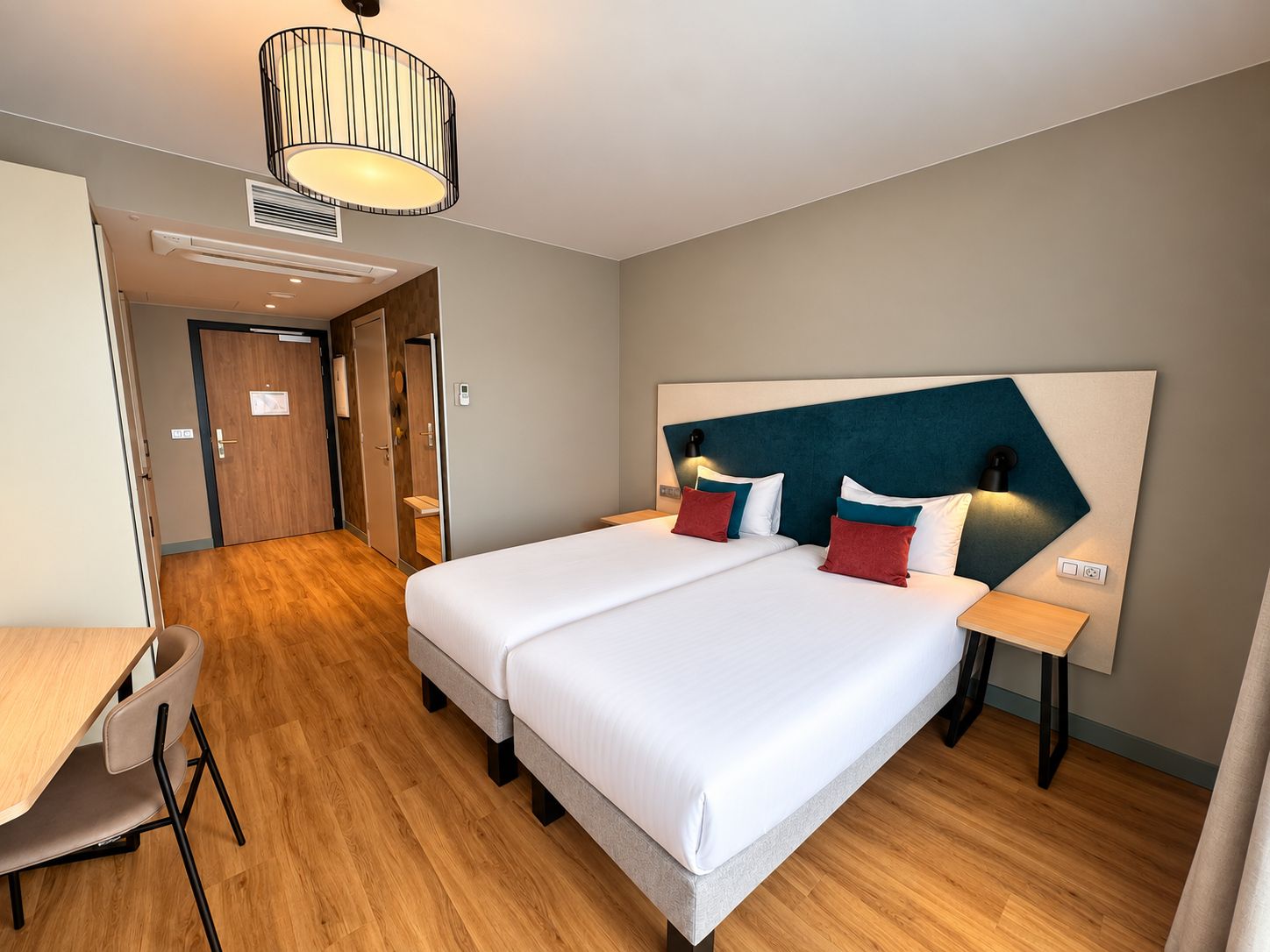 Ein Hotelzimmer mit Doppelbett, Nachttischen, Schreibtisch und Stuhl.