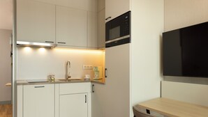 A compact kitchen with white cabinets, a microwave, a coffee machine, and a small dining table. - Adagio Antwerp City Center (Antwerp)