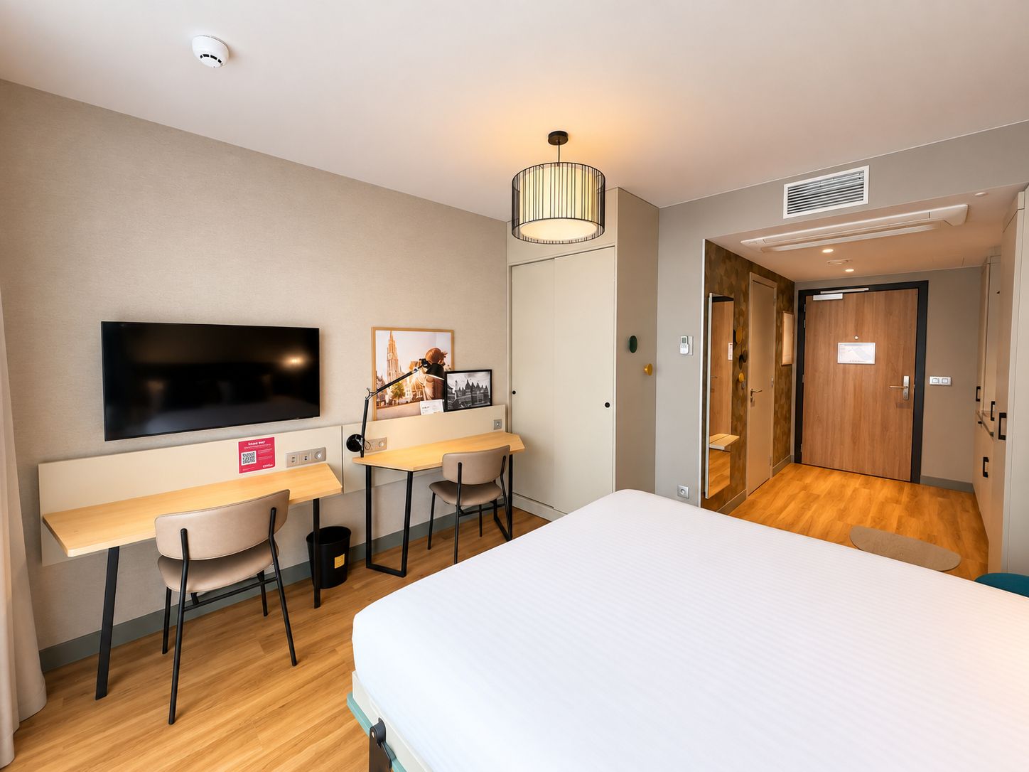 A hotel room with a bed, desk, chair, television, and a door leading to a bathroom.