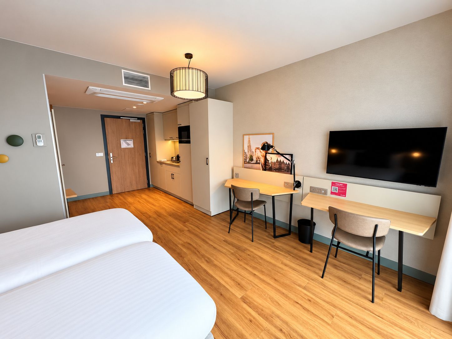 Une chambre d’hôtel avec un lit, un bureau et une chaise, une télévision et un tableau au mur.