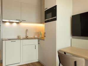 A compact kitchen with white cabinets, a microwave, a coffee machine, and a small table. - Adagio Antwerp City Center (Antwerp)