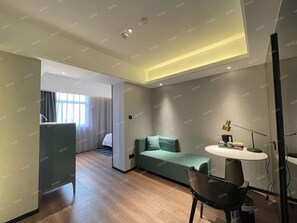 A modern hotel room with a sofa, a dining table, and a desk. - Ramada Encore by Wyndham Guangzhou Jiangnan West (Guangzhou)