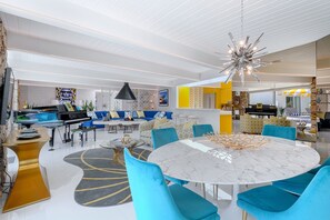 A modern living room with a round marble table, blue chairs, and a black pendant light. - Midcentury Masterpiece in Deepwell Estates - Pool and View  (Palm Springs)