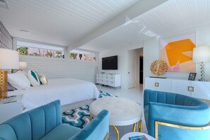 A modern bedroom with a large bed, a TV, and a blue armchair. - Midcentury Masterpiece in Deepwell Estates - Pool and View  (Palm Springs)