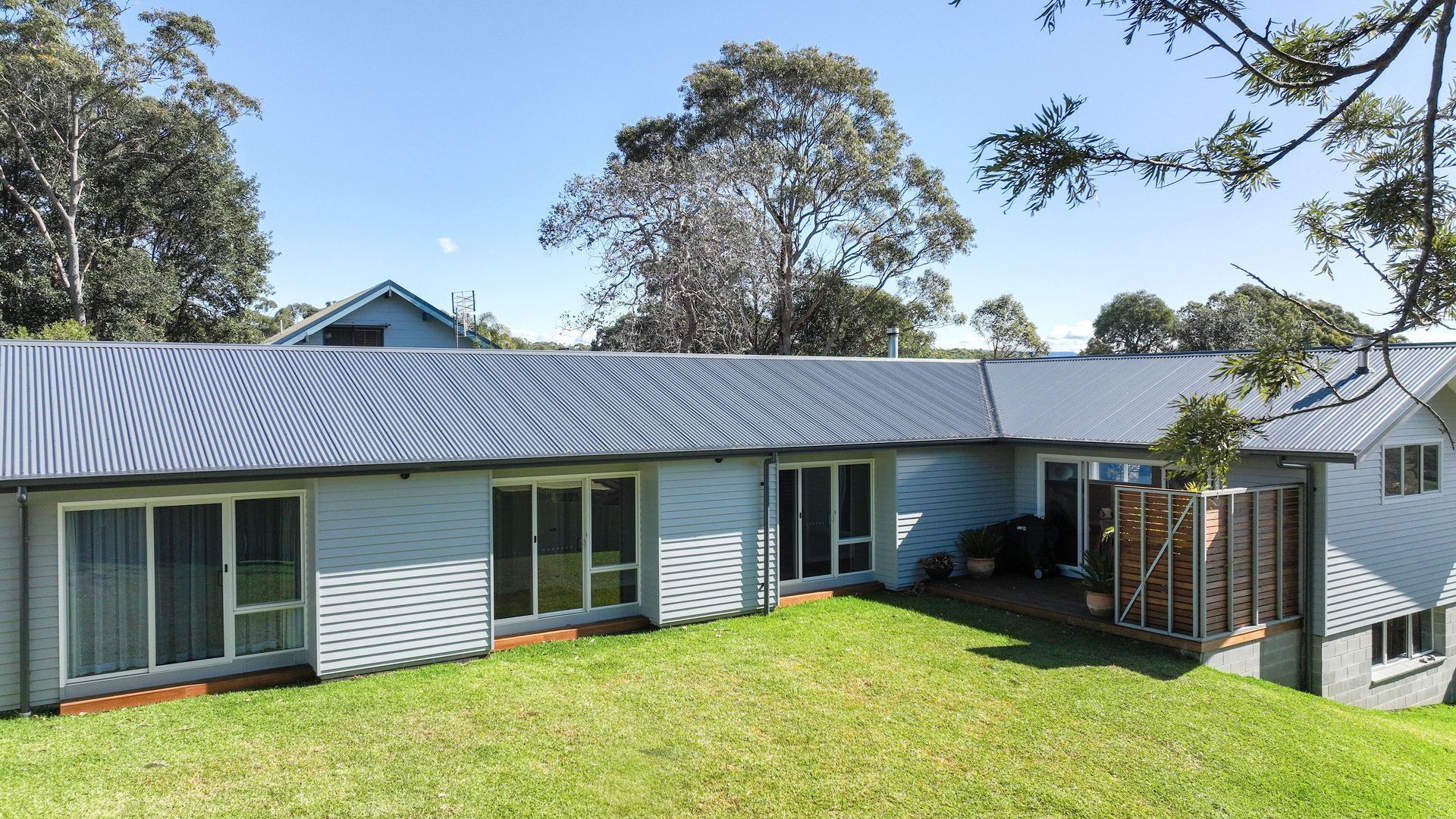 A modern two-story house with a sloped roof, large windows, and a well-maintained lawn.