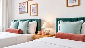 A hotel room with two beds, a nightstand with a lamp and a mug, and framed pictures on the wall. - Villa Antonio | Art Deco Stay on Ocean Drive (Miami Beach)