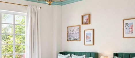 A hotel room with two beds, a ceiling with a leaf pattern, and framed pictures on the wall.