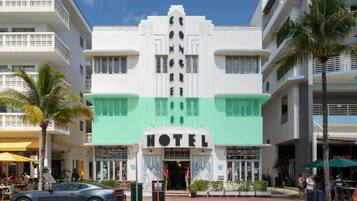 Un hôtel avec une entrée principale, plusieurs étages et un auvent vert.
