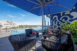 A rooftop pool area with lounge chairs and a large umbrella.