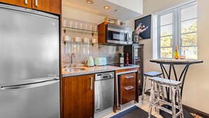Een moderne keuken met roestvrijstalen apparatuur, houten keukenkastjes en een klein eetgedeelte met een tafel en krukken.