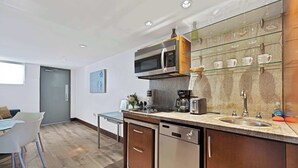 Una cocina moderna con microondas integrado, cafetera y estantes de vidrio sobre el lavamanos.