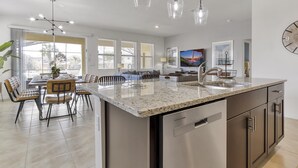 A modern kitchen with a central island, stainless steel appliances, and pendant lighting.