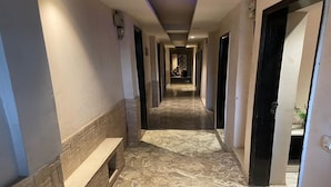 A hallway with a bench, tiled floor, and doors leading to rooms. - Hotel Pace Hero Honda Chowk (Gurugram)