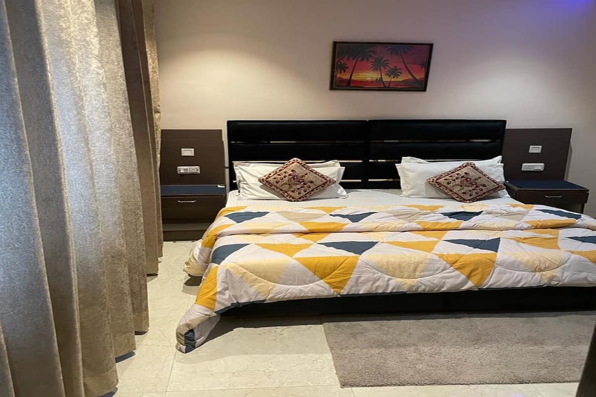 Ein Schlafzimmer mit Bett, Nachttischen, einem Gemälde und einem Vorhang.
