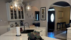 A modern kitchen with a marble countertop, pendant lighting, and a central island with seating. - V&V Resort (Greensboro)