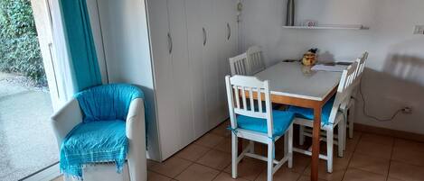 A dining area with a table and chairs, a window with curtains, and a door.