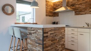 Une cuisine moderne dotée d’un îlot central, de tabourets de bar et d’un luminaire suspendu.