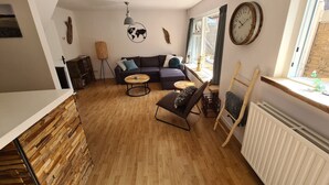 Un salon chaleureux avec un canapé, deux tables rondes, un fauteuil et une carte du monde accrochée au mur.