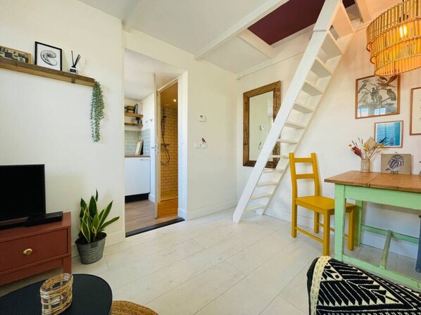Una sala de estar moderna con una escalera, un comedor y una cocina visible a través de un puerta abierta.