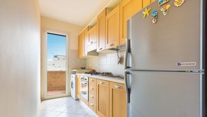 A modern kitchen with wooden cabinets, a stainless steel refrigerator, and a washing machine. - Casa La Torre by BarbarHouse (Torre Mozza)