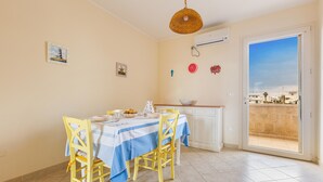 A dining area with a table set for two, a yellow chair, a blue and white tablecloth, and a hanging light fixture. - Casa La Torre by BarbarHouse (Torre Mozza)