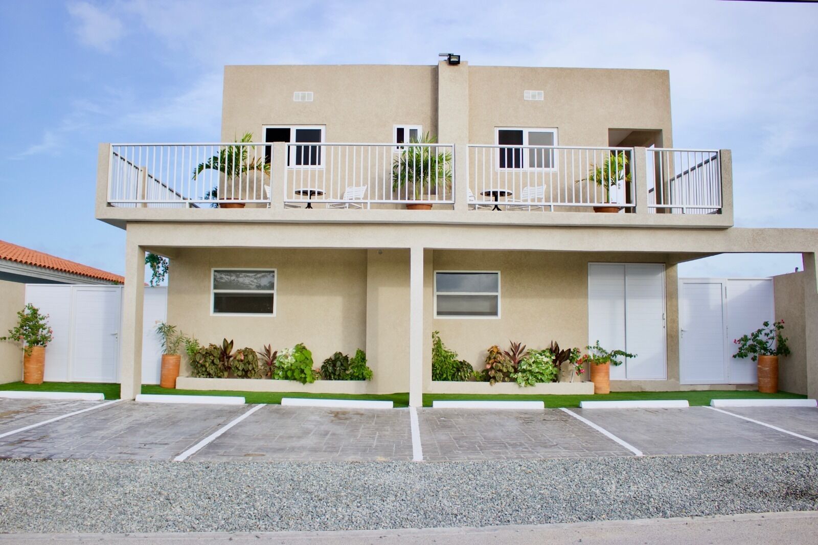 Un bâtiment à deux étages, doté d’un toit plat, d’un balcon à l’étage supérieur et d’un espace de stationnement à l’avant.