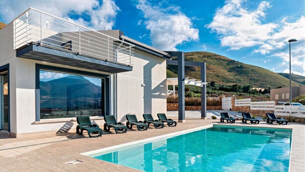 Un espace moderne aménagé au bord de la piscine, offrant une vue dégagée sur une montagne en arrière-plan.