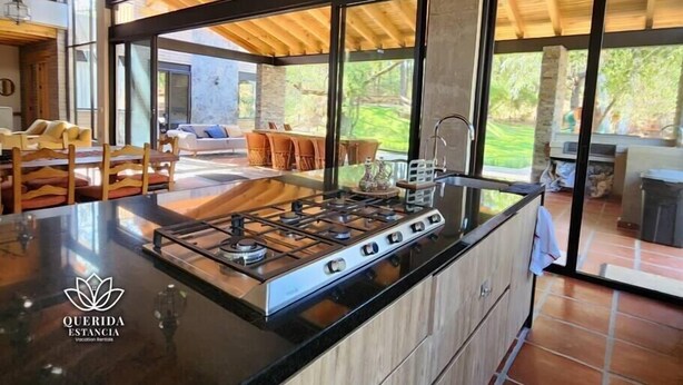 A modern kitchen with a large island, large windows, and a view of the outdoor patio area.