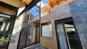 A modern building with large glass windows, a wooden ceiling, and stone accents.